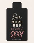A black grip mat with a motivational quote printed on it. The text reads 'One MORE REP but make it SEXY' in white and pink lettering, with 'grip mat studio' at the bottom.