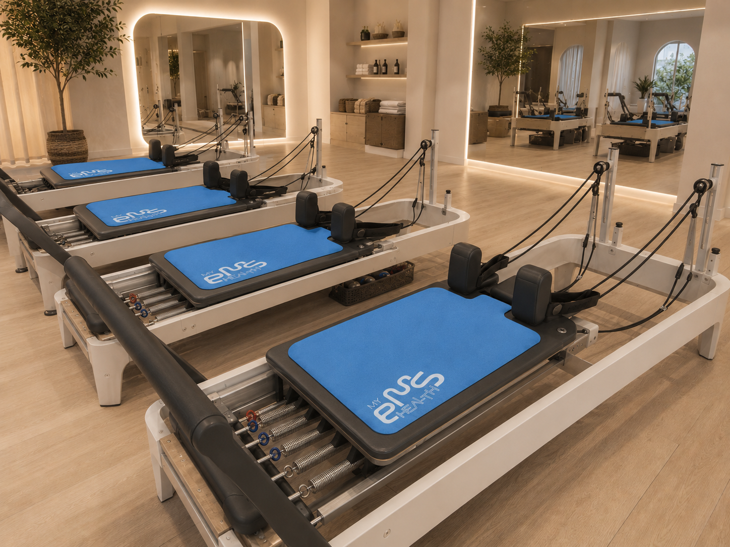Three Pilates reformer machines arranged in a row inside a bright, modern fitness studio with wood floors and mirrors.