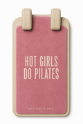 A pink Pilates grip mat with a beige frame and handle, featuring the text 'HOT GIRLS DO PILATES' in beige on the front, by grip mat studio.