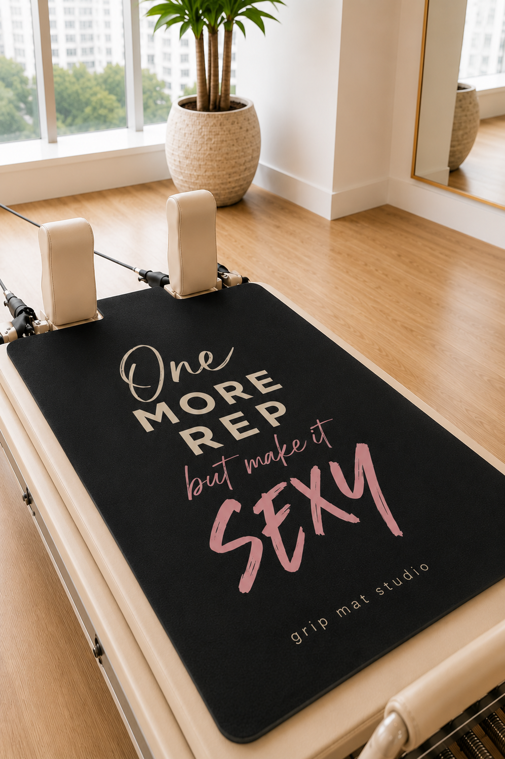 A Pilates reformer machine with a black grip mat featuring the motivational quote 'One MORE REP but make it SEXY' in white and pink lettering. The mat is branded with 'grip mat studio' in the bottom right corner.