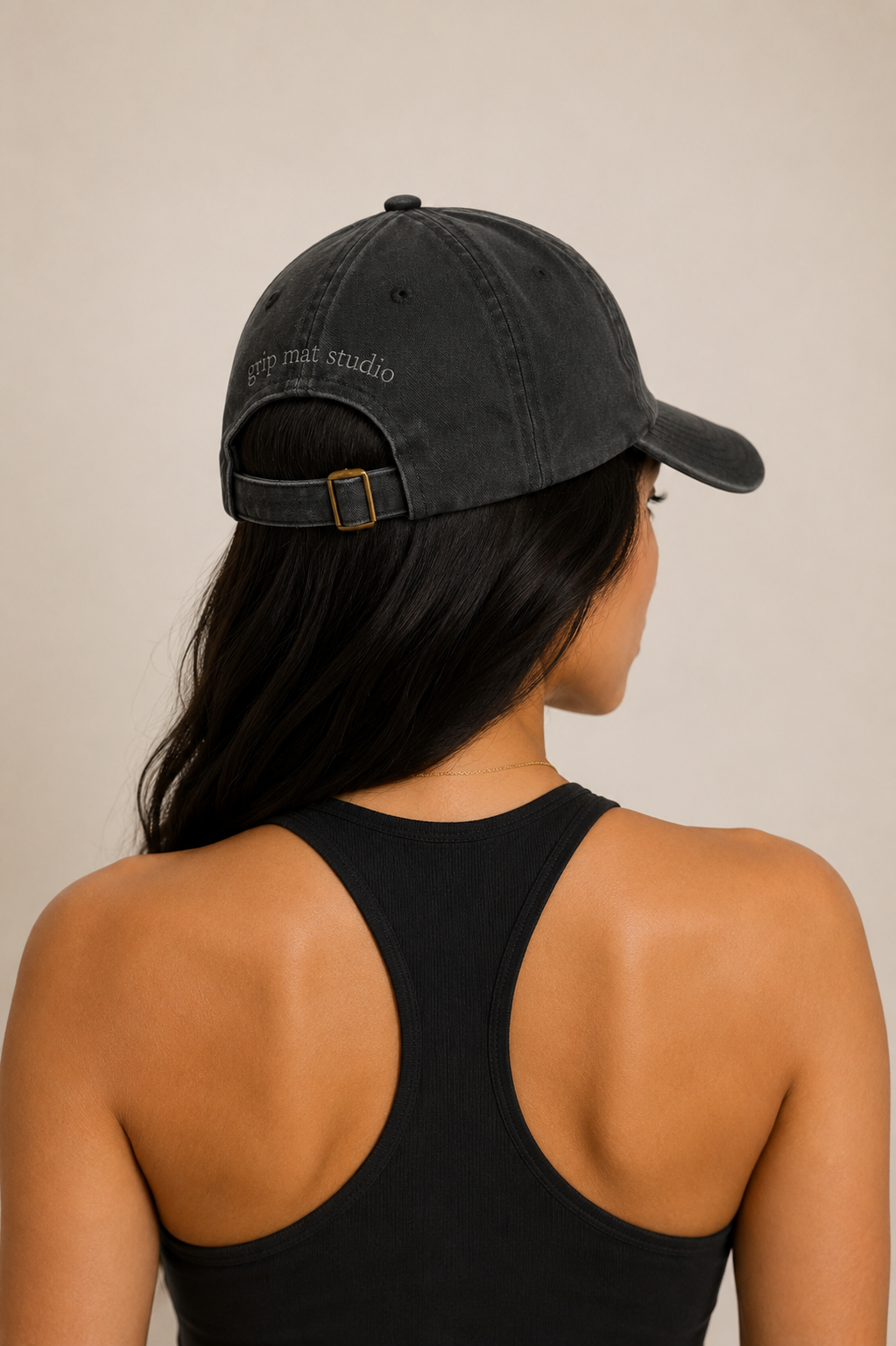 Back view of woman wearing charcoal Pilates hat with tonal Grip Mat Studio logo